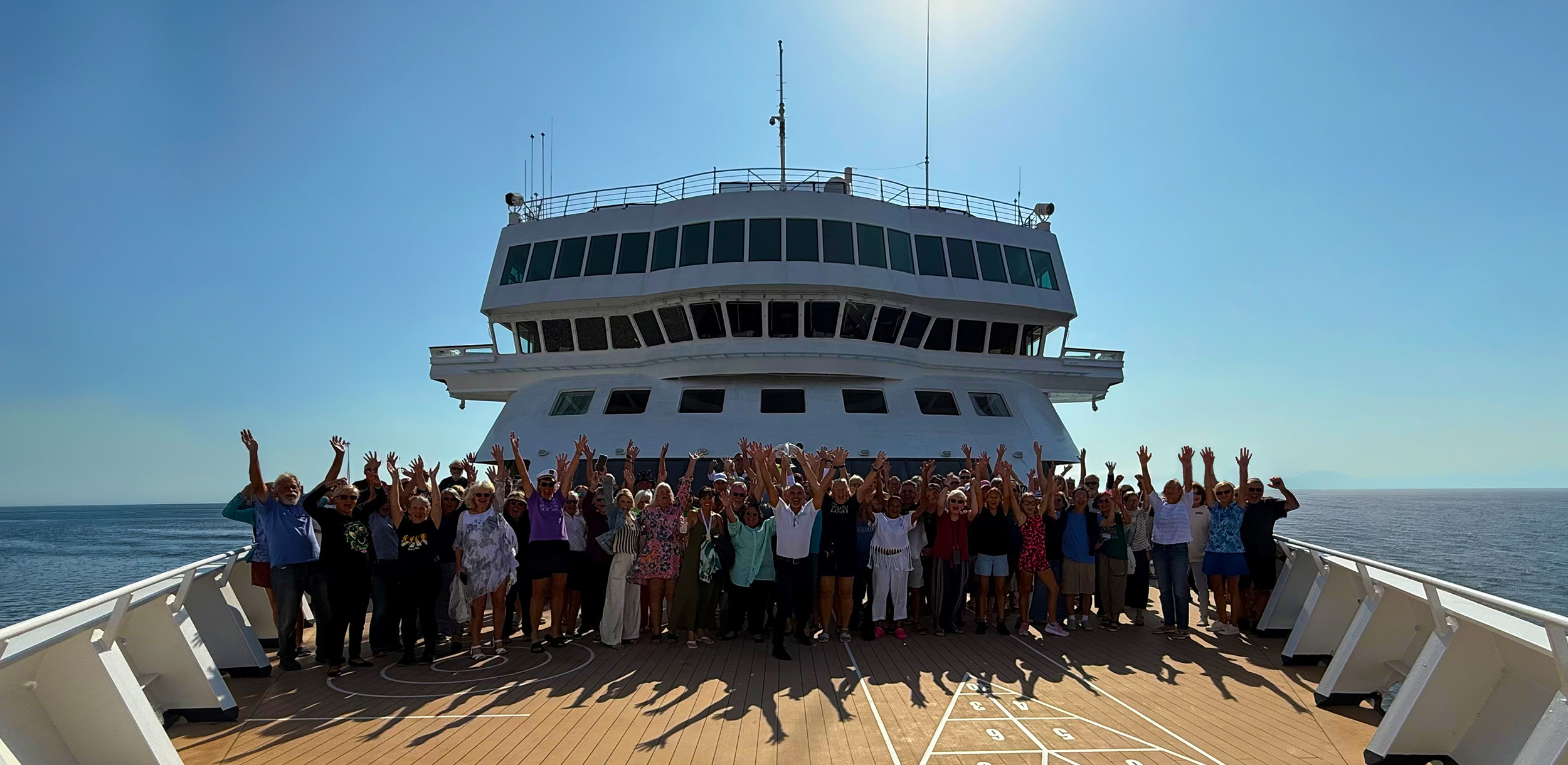 Residents cheering with their arms up on the bow of the ship